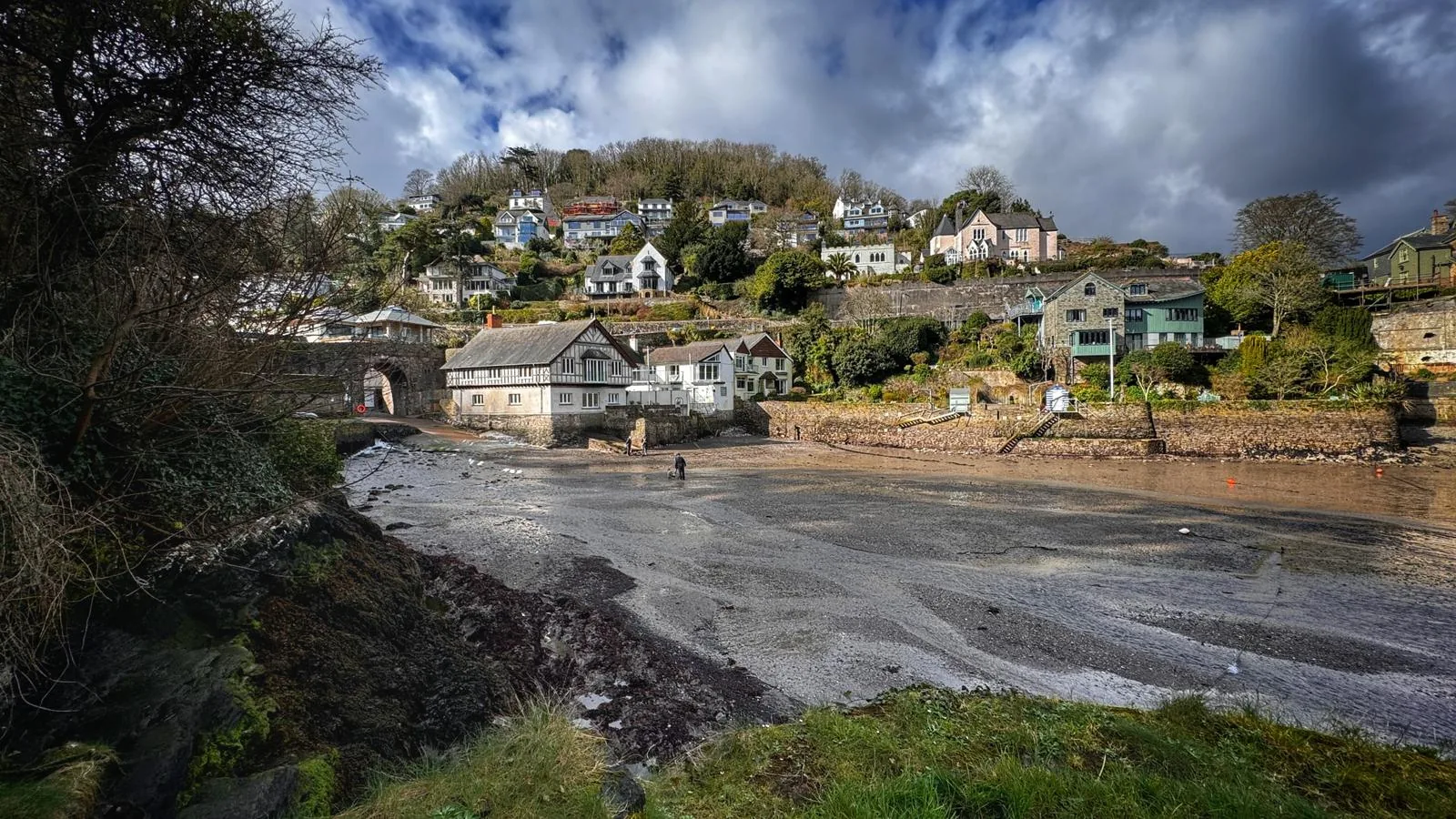 Quiet estuary cove at low tide with wooded hillside