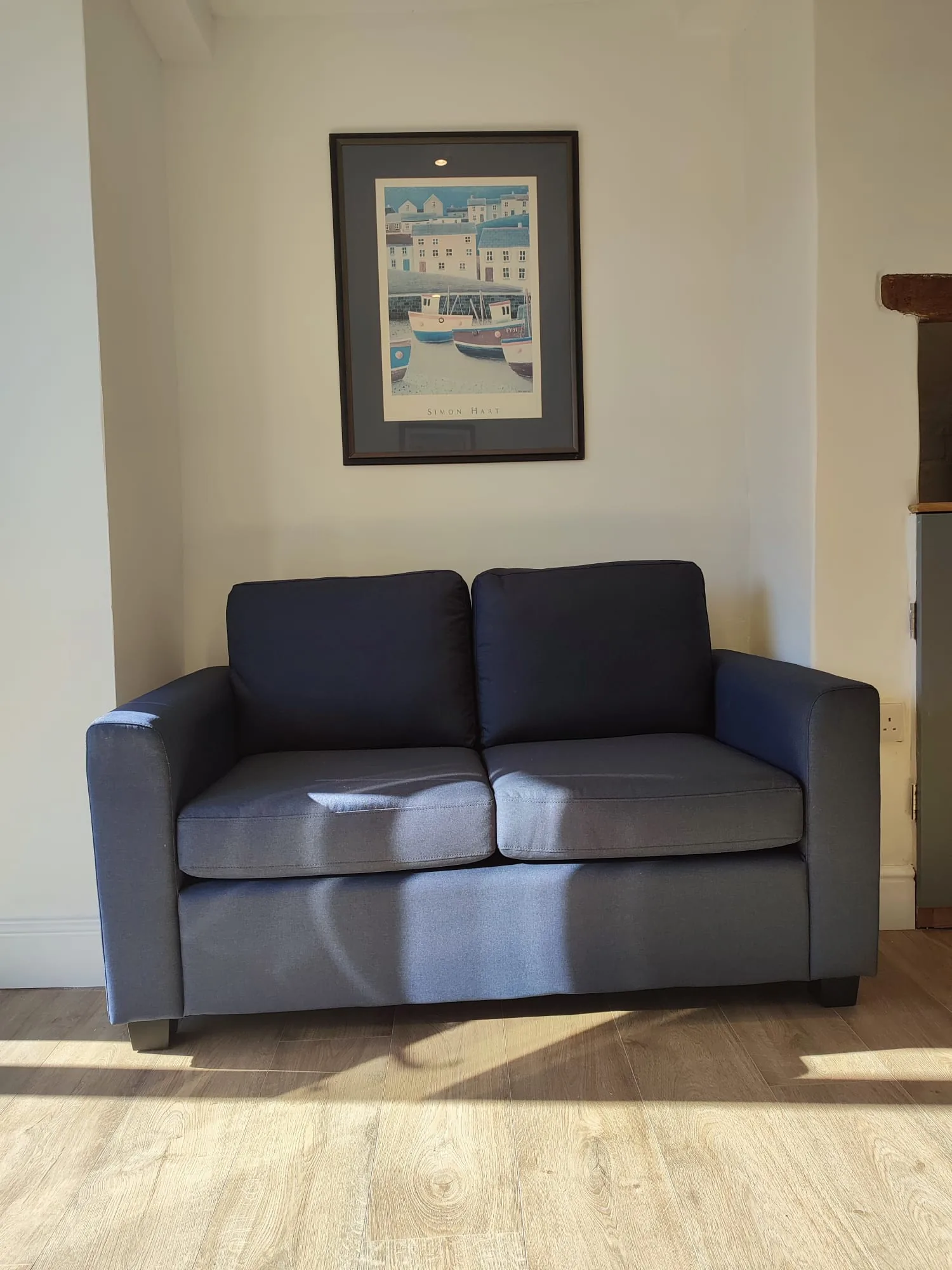 Navy sofa with framed harbour artwork above